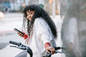Bike rider smiles while holding phone and resting hand on bicycle handle